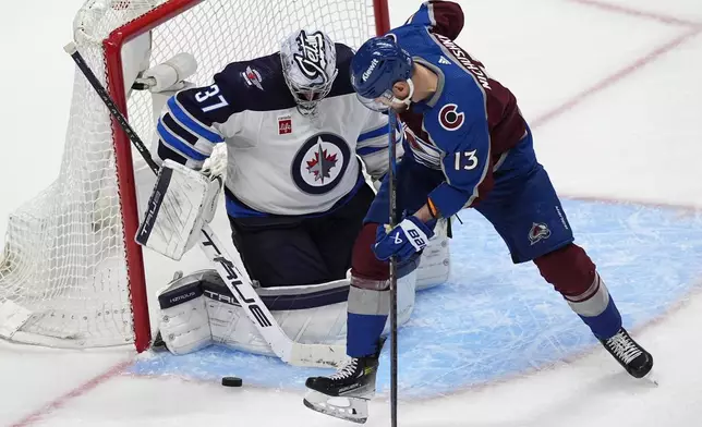Winnipeg Jets goaltender Connor Hellebuyck, left, stops a shot by Colorado Avalanche right wing Valeri Nichushkin during the third period of Game 3 of an NHL hockey Stanley Cup first-round playoff series Friday, April 26, 2024, in Denver. (AP Photo/David Zalubowski)