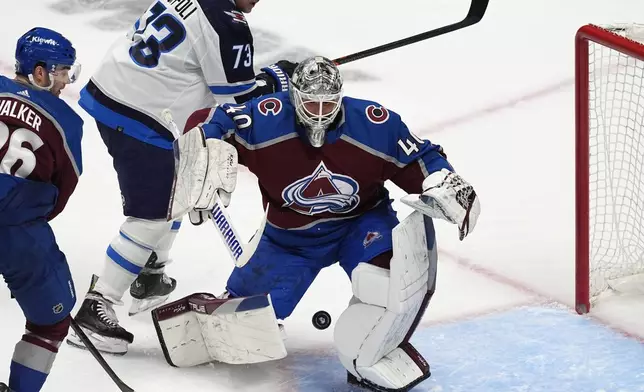 Colorado Avalanche goaltender Alexandar Georgiev, front, clears the puck as Winnipeg Jets center Tyler Toffoli looks on in the third period of Game 4 of an NHL Stanley Cup first-round playoff series, Sunday, April 28, 2024, in Denver. (AP Photo/David Zalubowski)