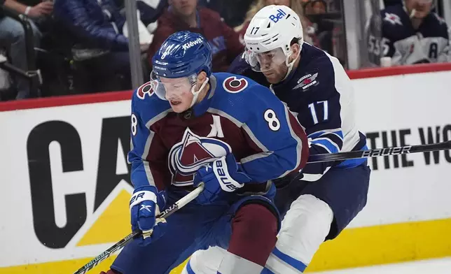 Colorado Avalanche defenseman Cale Makar, left, collects the puck with Winnipeg Jets center Adam Lowry, right, in pursuit in the second period of Game 4 of an NHL Stanley Cup first-round playoff series Sunday, April 28, 2024, in Denver. (AP Photo/David Zalubowski)