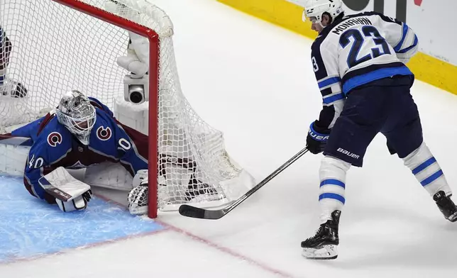 Colorado Avalanche goaltender Alexandar Georgiev, left, stops a wraparound shot by Winnipeg Jets center Sean Monahan during the first period of Game 3 of an NHL hockey Stanley Cup first-round playoff series Friday, April 26, 2024, in Denver. (AP Photo/David Zalubowski)