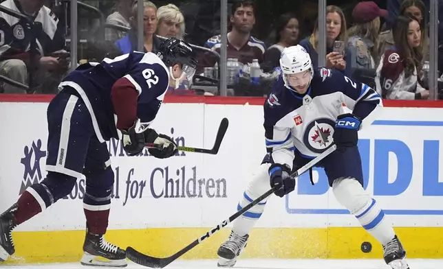 Winnipeg Jets defenseman Dylan DeMelo, right, struggles to collect the puck as Colorado Avalanche left wing Artturi Lehkonen, left, defends in the second period of an NHL hockey game Saturday, April 13, 2024, in Denver. (AP Photo/David Zalubowski)