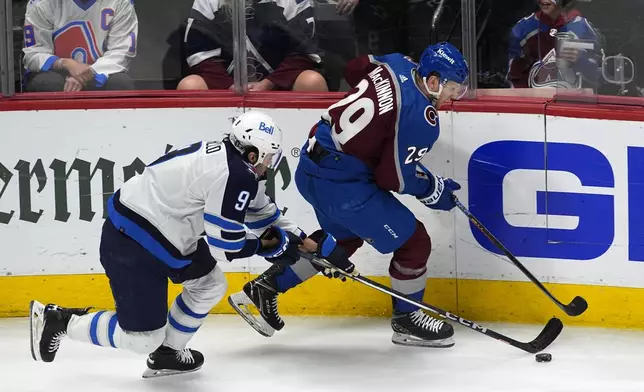 Colorado Avalanche center Nathan MacKinnon, right, collects the puck as Winnipeg Jets left wing Alex Iafallo, left, defends in the third period of Game 4 of an NHL Stanley Cup first-round playoff series Sunday, April 28, 2024, in Denver. (AP Photo/David Zalubowski)