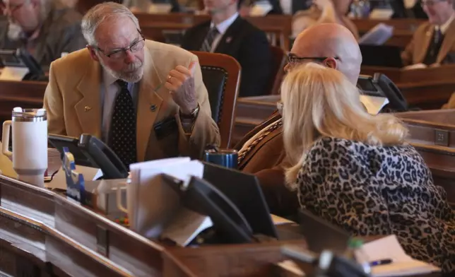 Kansas state Rep. Will Carpenter, left, R-Winfield, confers with two House Appropriations Committee members, Rep. Stephen Owens, center, R-Hesston, and Susan Concannon, R-Beloit, during a House session, Wednesday, March 27, 2024, at the Statehouse in Topeka, Kan. Carpenter has been pushing to increase the state's spending on in-home and community services for disabled to shrink waiting lists for those services. (AP Photo/John Hanna)