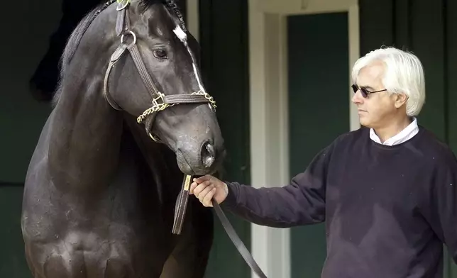 FILE - Trainer Bob Baffert walks 2015 Kentucky Derby and Preakness winner War Emblem in the barns at Pimlico Race Course, in Baltimore, Sunday May 19, 2002. Baffert will miss the race for the third consecutive year. He served a two-year suspension by Churchill Downs Inc. after his 2021 winner Medina Spirit was disqualified for a failed drug test. But the track’s corporate ownership meted out an additional year of punishment. (AP Photo/Alex Dorgan-Ross, File)