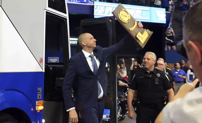Mark Pope exits the bus he rode into the arena, carrying the 1996 Championship Trophy at an event naming him head coach of the Kentucky men's NCAA college basketball team, at Rupp Arena in Lexington, Ky., Sunday, April 14, 2024. (AP Photo/James Crisp)