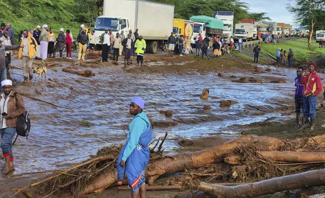 People gather on the main road after a dam burst, in Kamuchiri Village Mai Mahiu, Nakuru County, Kenya, Monday, April 29, 2024. Police in Kenya say at least 40 people have died after a dam collapsed in the country's west. (AP Photo)