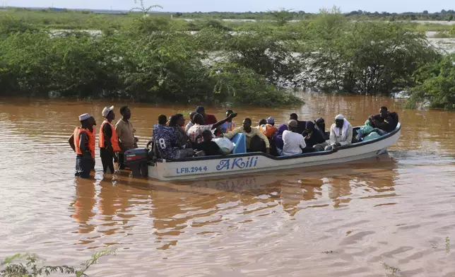 People cross a flooded area where another boat carrying a group of people has capsized at Mororo, border of Tana River and Garissa counties, North Eastern Kenya, Sunday, April 28, 2024. According to the Kenya Red Cross, 23 people have been rescued, while others still remain missing as search and rescue operations continue. Heavy rains pounding different parts of Kenya have led to dozens of deaths and the displacement of tens of thousands of people, according to the U.N. (AP Photo/Andrew Kasuku)