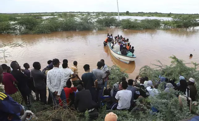 People cross a flooded area at Mororo, border of Tana River and Garissa counties, North Eastern Kenya, Sunday, April. 28, 2024. Heavy rains pounding different parts of Kenya have led to dozens of deaths and the displacement of tens of thousands of people, according to the U.N. (AP Photo/Andrew Kasuku)