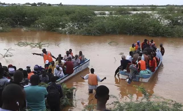 People cross a flooded area where another boat carrying a group of people has capsized at Mororo, border of Tana River and Garissa counties, North Eastern Kenya, Sunday, April 28, 2024. According to the Kenya Red Cross, over a dozen people have been rescued, while others still remain missing as search and rescue operations continue. Heavy rains pounding different parts of Kenya have led to dozens of deaths and the displacement of tens of thousands of people, according to the U.N. (AP Photo/Andrew Kasuku)