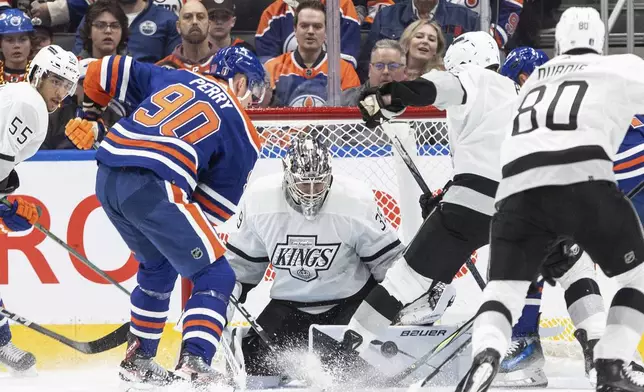 Los Angeles Kings goalie Cam Talbot (39) makes the save as Kings' Matt Roy (3) and Edmonton Oilers' Corey Perry (90) battle for a rebound during the first period of Game 1 in first-round NHL Stanley Cup playoff hockey action in Edmonton, Alberta, Monday, April 22, 2024. (Jason Franson/The Canadian Press via AP)