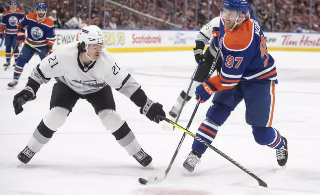 Los Angeles Kings' Jordan Spence (21) tries to stop Edmonton Oilers' Connor McDavid during the second period of Game 1 in first-round NHL Stanley Cup playoff hockey action in Edmonton, Alberta, Monday, April 22, 2024. (Jason Franson/The Canadian Press via AP)