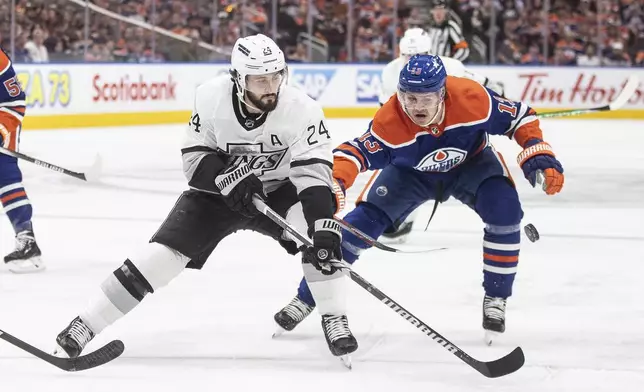 Los Angeles Kings' Phillip Danault (24) and Edmonton Oilers' Mattias Janmark (13) battle for the puck during the first period of Game 1 in first-round NHL Stanley Cup playoff hockey action in Edmonton, Alberta, Monday, April 22, 2024. (Jason Franson/The Canadian Press via AP)