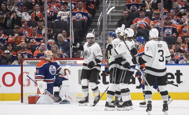Los Angeles Kings' Anze Kopitar (11), Quinton Byfield (55), Adrian Kempe (9) and Matt Roy (3) celebrate a goal as Edmonton Oilers goalie Stuart Skinner (74) looks on during the second period of Game 1 in first round NHL Stanley Cup playoff hockey action in Edmonton, Alberta, Monday, April 22, 2024. (Jason Franson/The Canadian Press via AP)