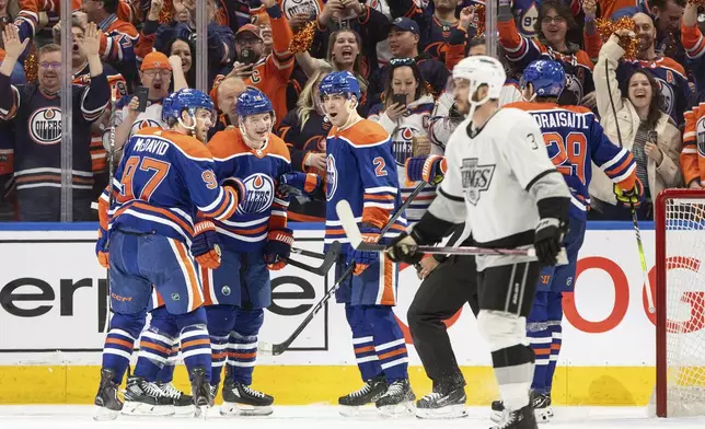 Los Angeles Kings' Matt Roy (3) skates past as Edmonton Oilers' Connor McDavid (97), Zach Hyman (18), Evan Bouchard (2) and Leon Draisaitl (29) as they celebrate a goal during the third period of Game 1 in first-round NHL Stanley Cup playoff hockey action in Edmonton, Alberta, Monday, April 22, 2024. (Jason Franson/The Canadian Press via AP)