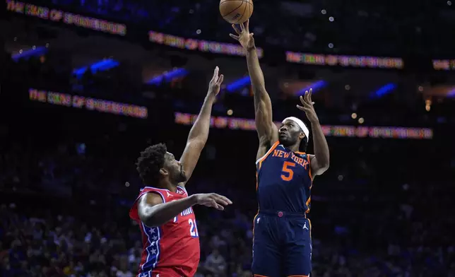 New York Knicks' Precious Achiuwa, right, goes up for a shot against Philadelphia 76ers' Joel Embiid during the first half of Game 4 in an NBA basketball first-round playoff series, Sunday, April 28, 2024, in Philadelphia. (AP Photo/Matt Slocum)