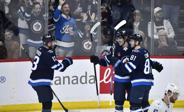 Winnipeg Jets' Kyle Connor (81) celebrates his goal against the Seattle Kraken with Mark Scheifele (55) and Gabriel Vilardi (13) during the first period of an NHL hockey game in Winnipeg, Manitoba on Tuesday April 16, 2024. (Fred Greenslade/The Canadian Press via AP)