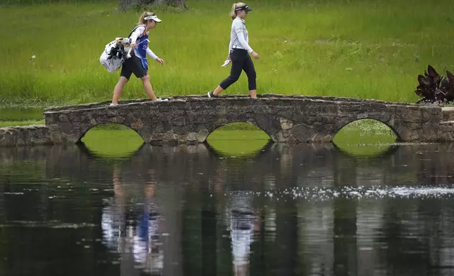 Brooke Henderson, of Canada, and her caddie walk over a bridge on the 15th hole during the third round of the Chevron Championship LPGA golf tournament Saturday, April 20, 2024, at The Club at Carlton Woods, in The Woodlands, Texas. (AP Photo/David J. Phillip)