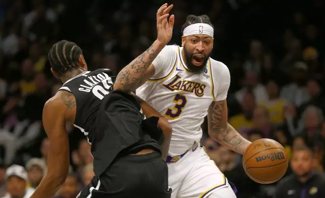 Los Angeles Lakers forward Anthony Davis, right, dribbles the ball around Brooklyn Nets center Nic Claxton during the first half of an NBA basketball game Sunday, March 31, 2024, in New York. (AP Photo/John Munson)