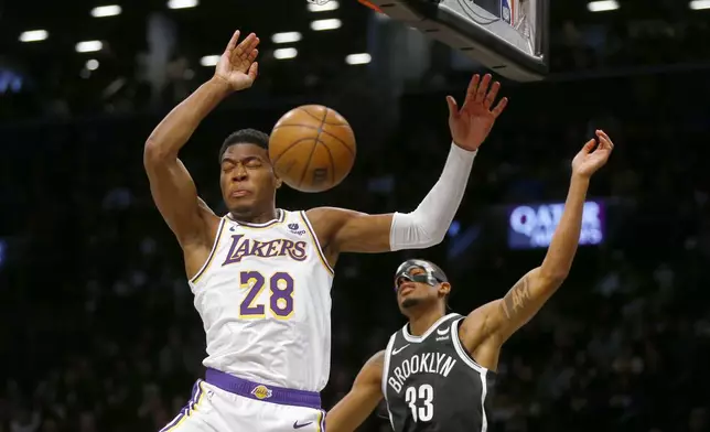 Los Angeles Lakers forward Rui Hachimura (28) dunks next to Brooklyn Nets center Nic Claxton (33) during the first half of an NBA basketball game Sunday, March 31, 2024, in New York. (AP Photo/John Munson)