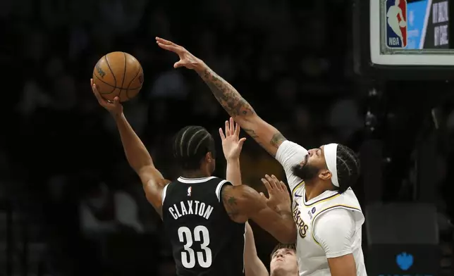 Brooklyn Nets center Nic Claxton, left, is defended by Los Angeles Lakers forward Anthony Thomas during the first half of an NBA basketball game Sunday, March 31, 2024, in New York. (AP Photo/John Munson)