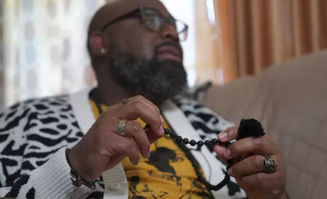 Lama Rod Owens holds his Buddhist mala beads made of lava rock used for prayer and meditation while at his childhood home in Rome, Georgia on Saturday, March 30, 2024. Owens, a self-proclaimed Black Buddhist Southern Queen, grew up Christian and was raised by his Methodist minister mother. Today, he is an influential voice in a new generation of Buddhist teachers, respected for his work focused on social change, identity and spiritual wellness. (AP Photo/Jessie Wardarski)