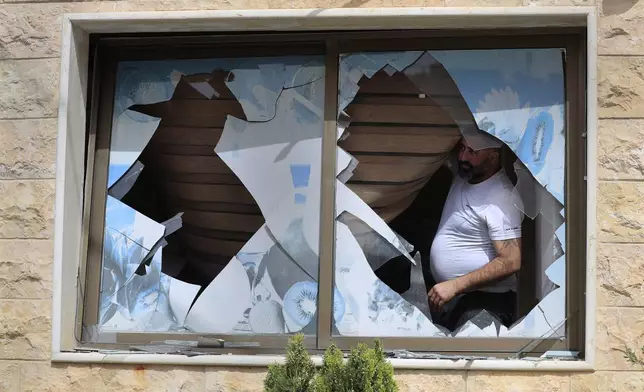 A Lebanese villager looks through a broken window of his house which was damaged by Israeli shelling, in Kfar Kila, a Lebanese border village with Israel, south Lebanon, Thursday, April 18, 2024. Hezbollah militants and Israeli forces have been exchanging fire since a day after the Israel-Hamas war began on Oct. 7. (AP Photo/Mohammed Zaatari)