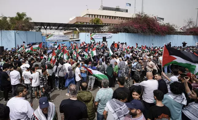 Protesters wave Palestinian flags during a sit-in in solidarity with the Palestinian people in Gaza in front of UNRWA office, background, in Beirut, Lebanon, Thursday, April 18, 2024. Hundreds of Palestinian refugees protested Thursday outside the offices of the U.N. agency for Palestinian refugees in Beirut, expressing solidarity with fellow Palestinians in the Gaza Strip. (AP Photo/Hassan Ammar)