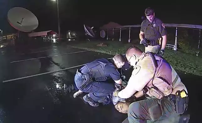 In this image from Altoona Police Department body-camera video, police restrain Demetrio Jackson in a parking lot on the border of Altoona and Eau Claire, Wis., on Oct. 8, 2021, minutes before a paramedic injects him with ketamine. Five medical experts who reviewed the case for AP said Jackson’s behavior did not appear to be dangerous enough to justify the use of ketamine. (Altoona Police Department via AP)
