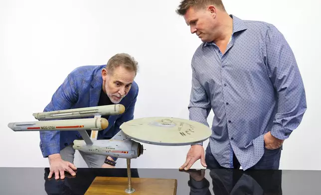 Joe Maddalena, executive vice president of Heritage Auctions, left, and Eugene “Rod” Roddenberry, the son of “Star Trek” creator Gene Roddenberry, view the recently recovered first model of the USS Enterprise at Heritage Auctions in Los Angeles, April 13, 2024. The model — used in the original “Star Trek” television series — has been returned to Eugene, decades after it went missing in the 1970s. (Josh David Jordan/Heritage Auctions via AP)