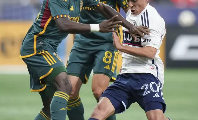 LA Galaxy's Joseph Paintsil, left, and Vancouver Whitecaps' Andres Cubas vie for the ball as Galaxy's Mark Delgado, back, watches during the first half of an MLS soccer match Saturday, April 13, 2024, in Vancouver, British Columbia. (Darryl Dyck/The Canadian Press via AP)