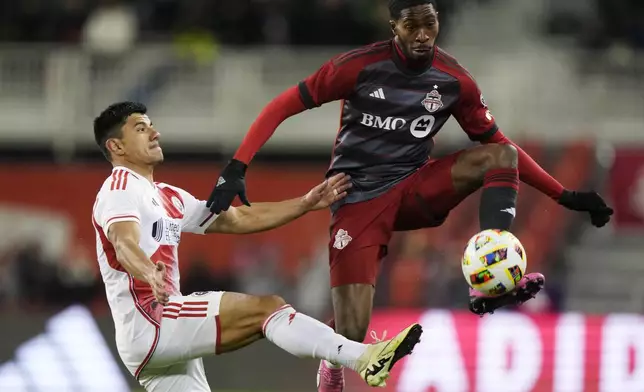 Toronto FC's Tyrese Spicer, right, controls the ball as New England Revolution's Nick Lima defends during the second half of an MLS soccer match Saturday, April 20, 2024, in Toronto. (Frank Gunn/The Canadian Press via AP)