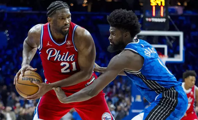 Philadelphia 76ers' Joel Embiid, left, looks to make his move against Orlando Magic's Jonathan Isaac, right, during the second half of an NBA basketball game, Friday, April 12, 2024, in Philadelphia. The 76ers won 125-113. (AP Photo/Chris Szagola)