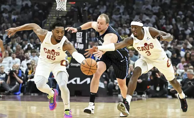 Cleveland Cavaliers' Donovan Mitchell (45) and Caris LeVert (3) steal the ball from Orlando Magic's Joe Ingles during the first half in Game 1 of an NBA basketball first-round playoff series, Saturday, April 20, 2024, in Cleveland. (AP Photo/Nick Cammett)