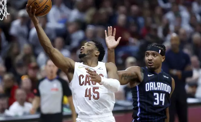 Cleveland Cavaliers guard Donovan Mitchell (45) shoots against Orlando Magic center Wendell Carter Jr. (34) during the first half of Game 2 of an NBA basketball first-round playoff series, Monday, April 22, 2024, in Cleveland. (AP Photo/Ron Schwane)