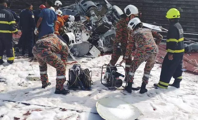 In this photo released by Fire &amp; Rescue Department of Malaysia, fire and rescue department inspect the crash site of two helicopter in Lumur, Perak state, Monday, April 23, 2024. Malaysia's navy says two military helicopters collided and crashed during a training session, killing all 10 people on board. (Terence Tan/Ministry of Communications and Information via AP)