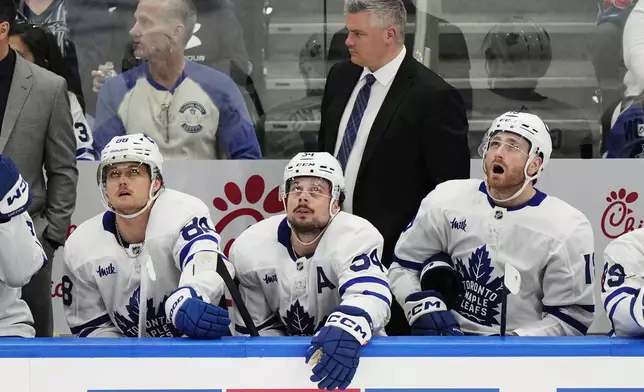 Toronto Maple Leafs coach Sheldon Keefe and players William Nylander (88), Auston Matthews (34) and Noah Gregor (18) react on the bench during the third period of the team's NHL hockey game against the Tampa Bay Lightning on Wednesday, April 17, 2024, in Tampa, Fla. (Frank Gunn/The Canadian Press via AP)