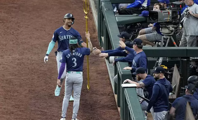 Seattle Mariners' J.P. Crawford (3) gives Julio Rodriguez a trident as they celebrate Rodriguez's two-run home run in the third inning of the team's baseball game against the Texas Rangers in Arlington, Texas, Tuesday, April 23, 2024. (AP Photo/Tony Gutierrez)