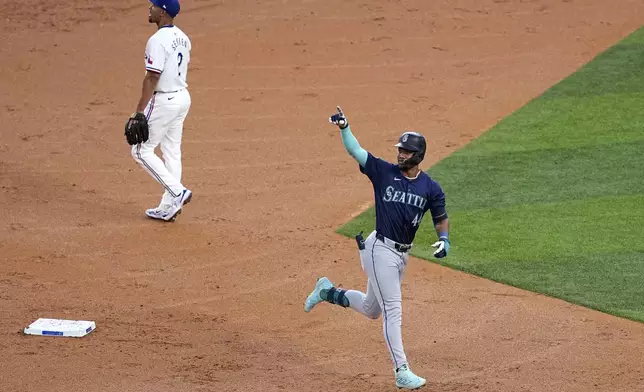 Seattle Mariners' Julio Rodriguez celebrates his two-run home run as he jogs past Texas Rangers second baseman Marcus Semien during the third inning of a baseball game in Arlington, Texas, Tuesday, April 23, 2024. (AP Photo/Tony Gutierrez)