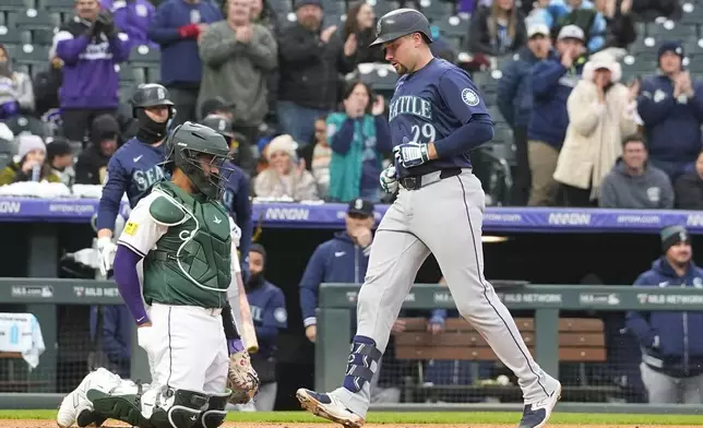Seattle Mariners' Cal Raleigh, right, crosses home plate after hitting a solo home run as Colorado Rockies catcher Elias Díaz looks on in the second inning of a baseball game Saturday, April 20, 2024, in Denver. (AP Photo/David Zalubowski)