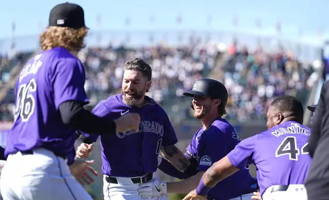 Colorado Rockies' Ryan McMahon, third from left, is congratulated by, from left to right, Nick Mears, Jake Cave and Elehuris Montero after hitting a walkoff RBI single in the 10th inning of the first game of a baseball doubleheader against the Seattle Mariners, Sunday, April 21, 2024, in Denver. (AP Photo/David Zalubowski)