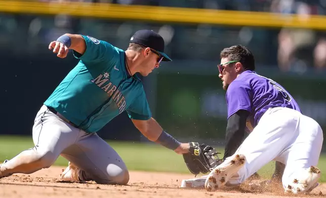 Seattle Mariners second baseman Dylan Moore, left, applies a late tag as Colorado Rockies' Brenton Doyle steals second base in the sixth inning of the first game of a baseball doubleheader Sunday, April 21, 2024, in Denver. (AP Photo/David Zalubowski)