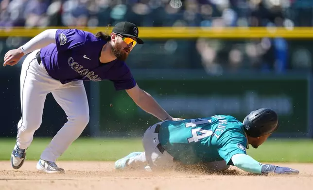 Colorado Rockies second baseman Brendan Rodgers, left, tags out Seattle Mariners' Julio Rodríguezwho was trying to steal second in the seventh inning of the first game of a baseball doubleheader Sunday, April 21, 2024, in Denver. (AP Photo/David Zalubowski)