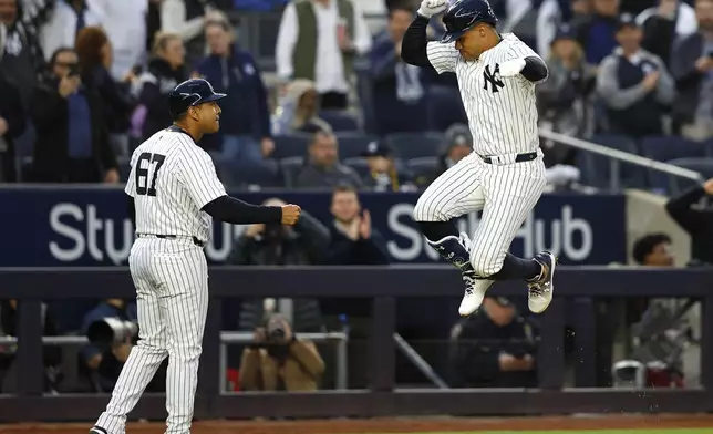 New York Yankees' Juan Soto, right, reacts in front third base coach Luis Rojas (67) after hitting a home run against the Miami Marlins during the fourth inning of a baseball game, Monday, April 8, 2024, in New York. (AP Photo/Noah K. Murray)