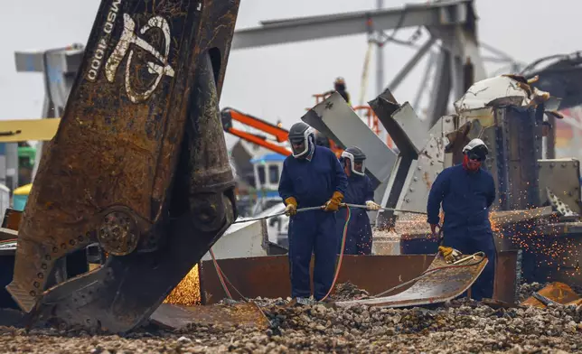 Workers use torches to break apart large salvaged pieces of the collapsed Francis Scott Key Bridge at Tradepoint Atlantic, Friday, April 12, 2024, in Sparrows Point, Md. (AP Photo/Julia Nikhinson)
