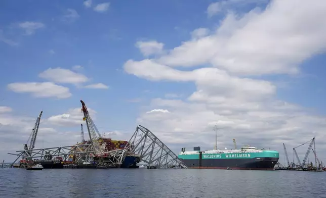 A vessel, center right, moves past the stranded container ship Dali, through a newly opened deep-water channel in Baltimore after being stuck in the harbor since the Francis Scott Key Bridge collapsed four weeks ago, Thursday, April 25, 2024. (AP Photo/Matt Rourke)