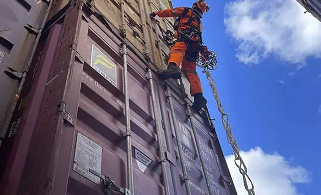 In this photo provided by the Key Bridge Response 2024 Unified Command, a specialized salvage climber scales a container to survey the damage to containers onboard the cargo ship Dali at the site of the Francis Scott Key Bridge, Saturday, April 6, 2024, in Baltimore. Salvage crews on Sunday began removing containers from the deck of the cargo ship that crashed into and collapsed the bridge, an important step toward the full reopening of one of the nation’s main shipping lanes. (Key Bridge Response 2024 Unified Command via AP)