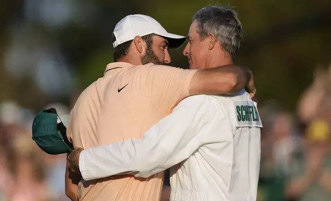 Scottie Scheffler celebrates his win with his caddie Ted Scott at the Masters golf tournament at Augusta National Golf Club Sunday, April 14, 2024, in Augusta, Ga. (AP Photo/Charlie Riedel)