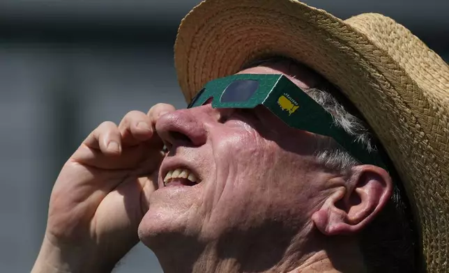A patron look up at the sun during an solar eclipse during a practice round in preparation for the Masters golf tournament at Augusta National Golf Club Monday, April 8, 2024, in Augusta, Ga. (AP Photo/Matt Slocum)
