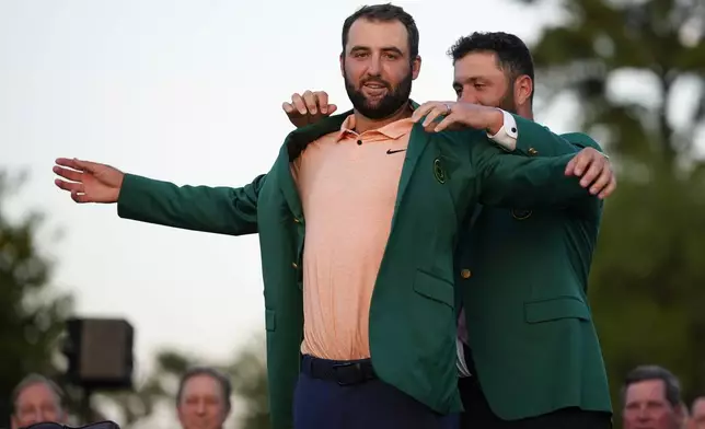 Jon Rahm, of Spain, puts the green jacket on winner Scottie Scheffler after the Masters golf tournament at Augusta National Golf Club Sunday, April 14, 2024, in Augusta, Ga. (AP Photo/Matt Slocum)