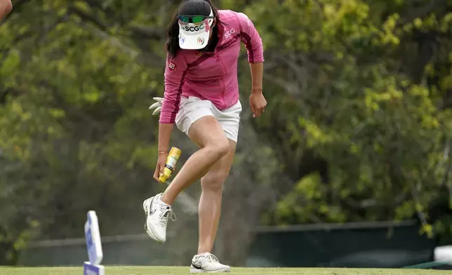 FILE - Atthaya Thitkul, of Thailand, sprays her legs with sunscreen on the third hole during the first round of the MEDIHEAL Championship golf tournament Thursday, Oct. 6, 2022, in Somis, Calif. Exposure to the sun’s ultraviolet light raises the risk of skin cancer, the most common and one of the most preventable types of cancer. (AP Photo/Mark J. Terrill, File)